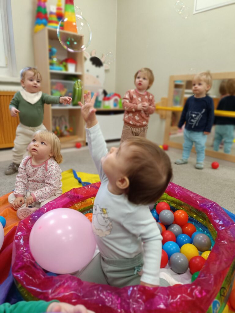Grupa maluchów bawiących się w basenie z piłeczkami i balonami