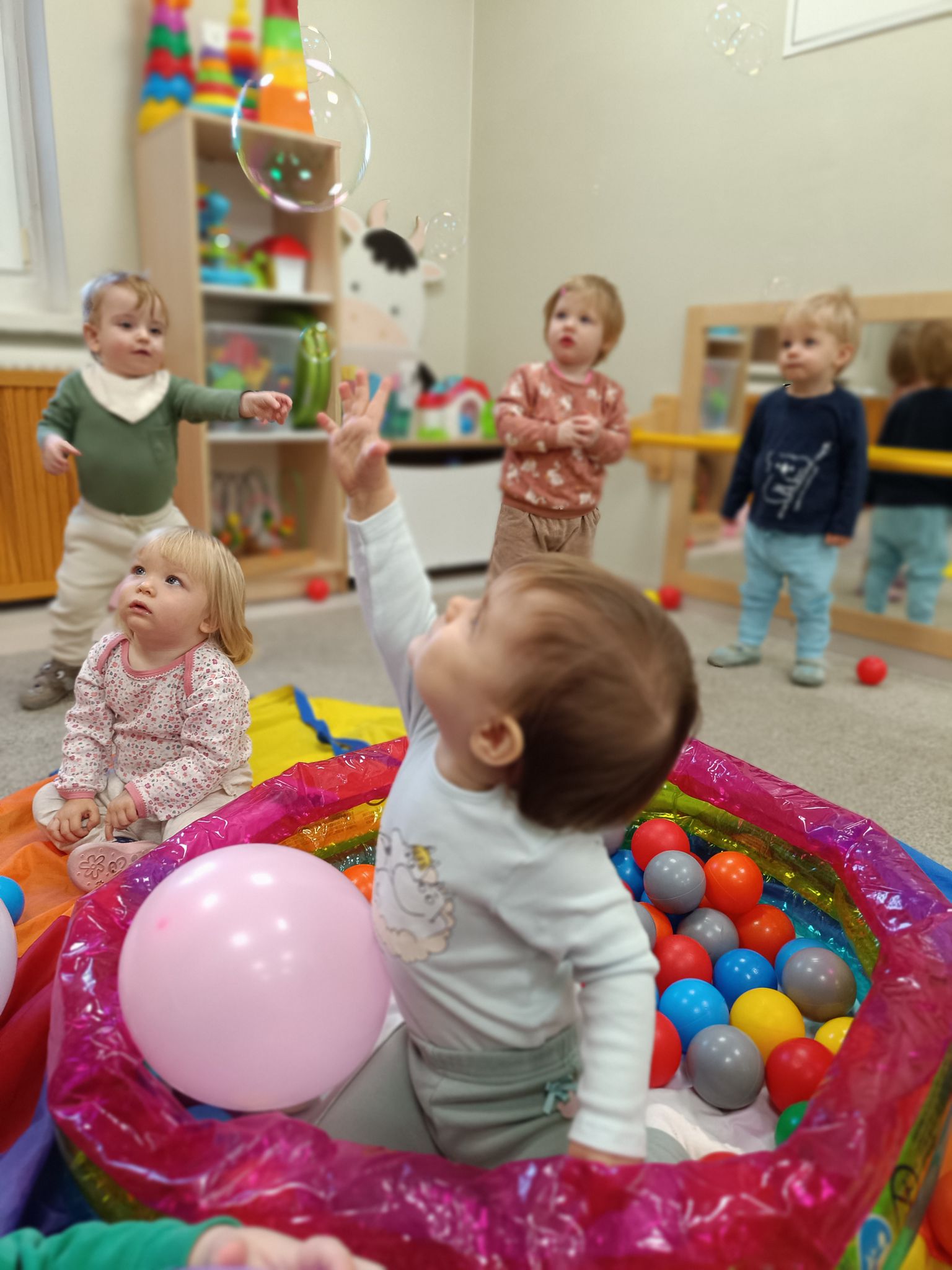 Grupa maluchów bawiących się w basenie z piłeczkami i balonami